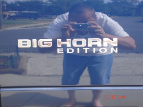1981 Ford Bronco - The 'Big Horn Edition' badge is visible on the side of a blue vehicle, with a person taking a photo reflected in the surface.