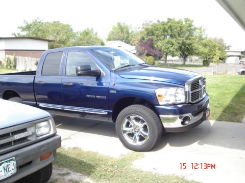 1981 Ford Bronco - A blue Dodge Ram 1500 pickup truck is parked next to another vehicle in a driveway.