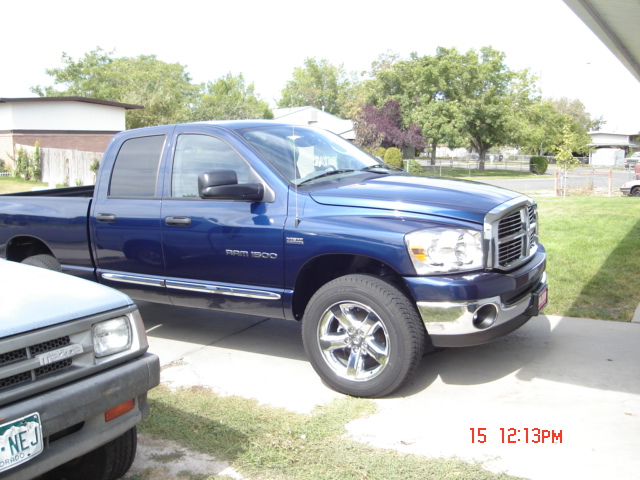 Blue Dodge Ram 1500 pickup truck, front quarter view, chrome wheels, parked on concrete