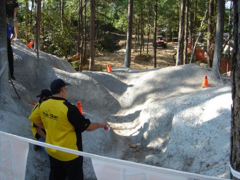 2002 Jeep Wrangler - An off-road course is set up in a wooded area, with spectators watching an ATV in the distance.