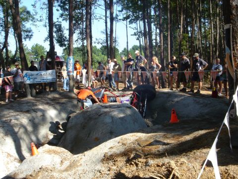 2002 Jeep Wrangler - Competitors navigate a challenging off-road course with a crowd observing the action.
