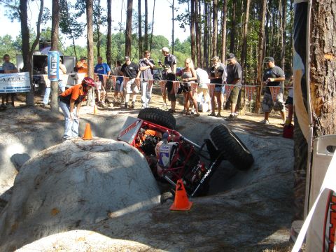2002 Jeep Wrangler - An off-road buggy is stuck on its side during a competition, with onlookers observing the scene.