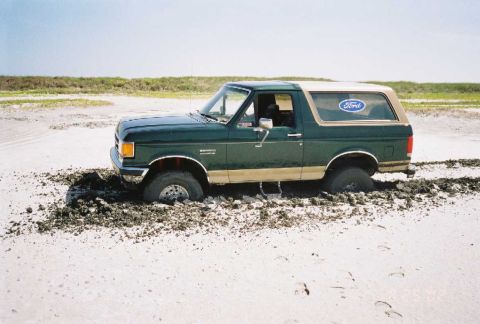 1990 Ford Bronco - This 1990 Ford Bronco is stuck deep in the mud on a sandy terrain.