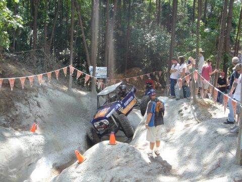 2002 Jeep Wrangler - A custom rock crawler navigates a challenging course during an off-road event, with onlookers observing the action.