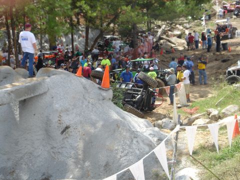 2002 Jeep Wrangler - An off-road vehicle has overturned during an event, with spectators watching from the sidelines.