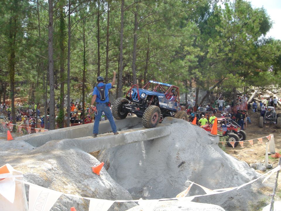 Blue tube-chassis rock buggy climbing rocks at off-road competition