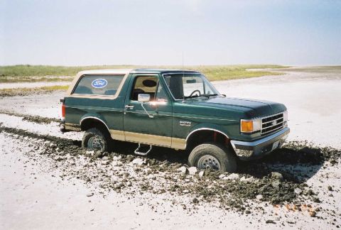 1990 Ford Bronco - This Ford Bronco is stuck in the mud, with its front right wheel submerged.