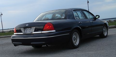 2000 Ford Crown Victoria - A black 2000 Ford Crown Victoria is parked outdoors near a body of water.