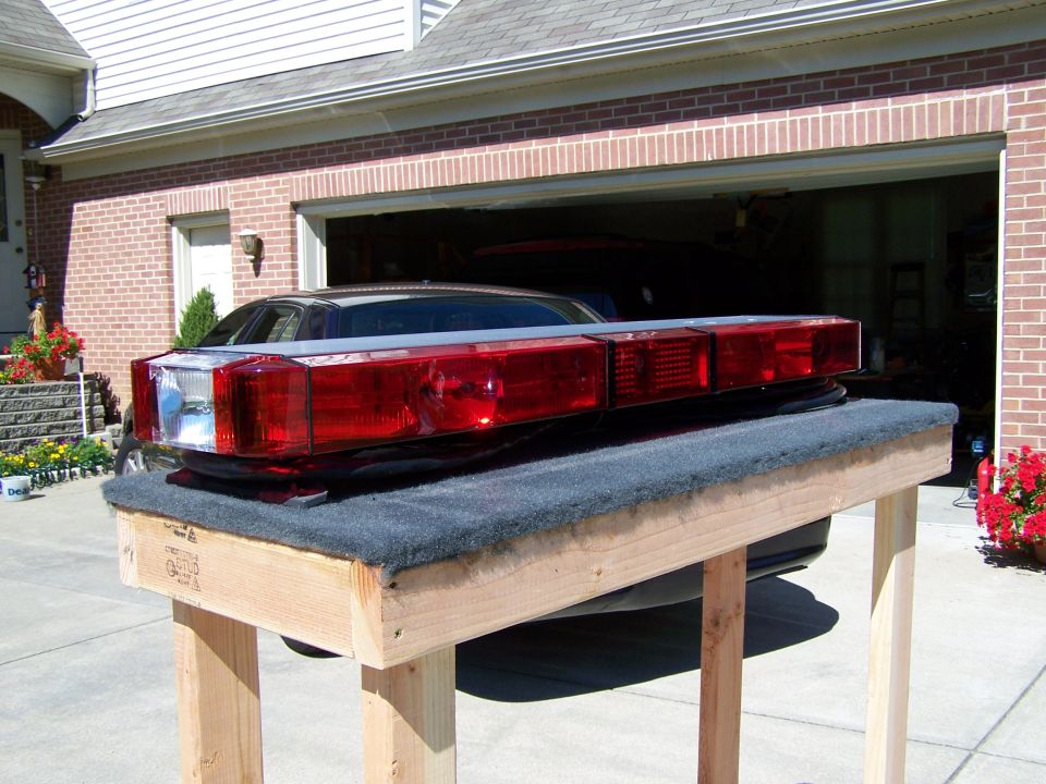 Emergency light bar with red and clear lenses on a wooden stand