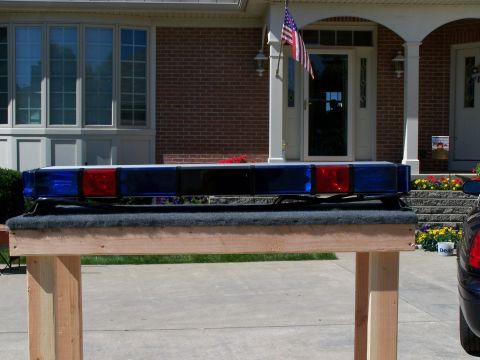 2003 Ford Crown Victoria - A light bar with blue and red lights is displayed on a stand in front of a residential building.