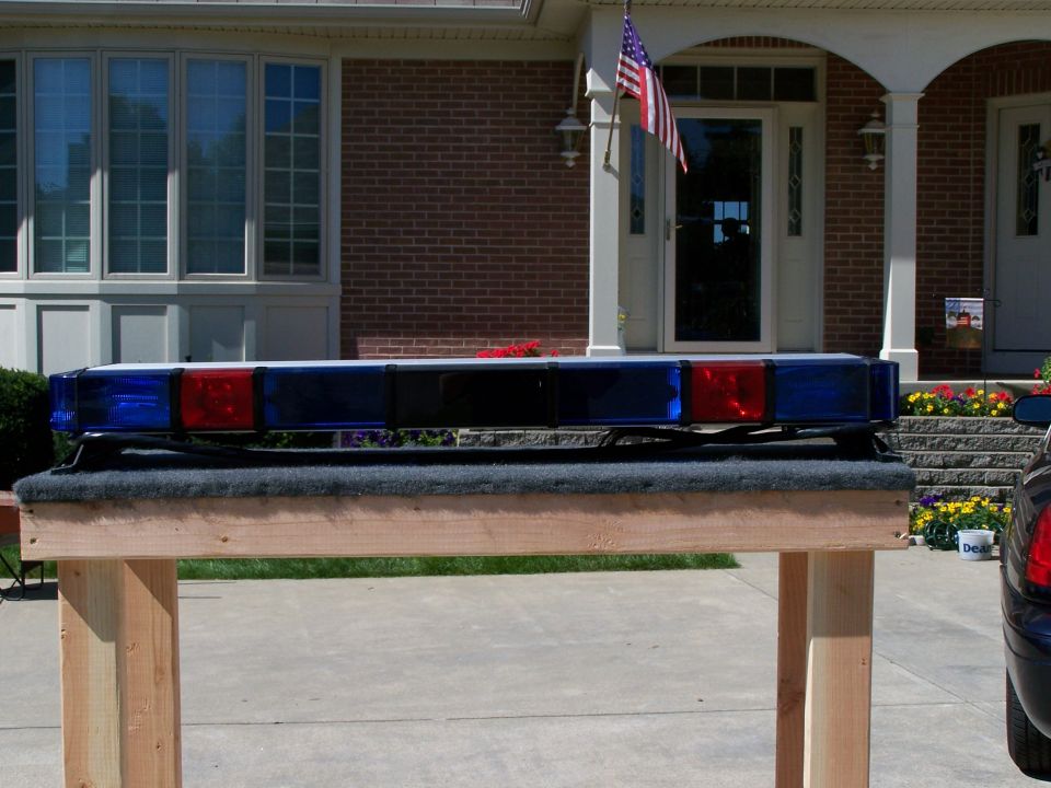 Light bar with blue and red lights on a wooden stand in front of a house