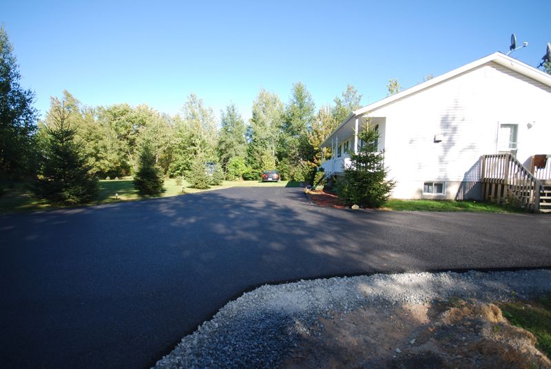 Dark SUV parked on a newly paved driveway in front of a white house