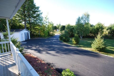 1996 Ford Bronco - A view of a driveway and a small shed, bordered by trees and a porch railing.