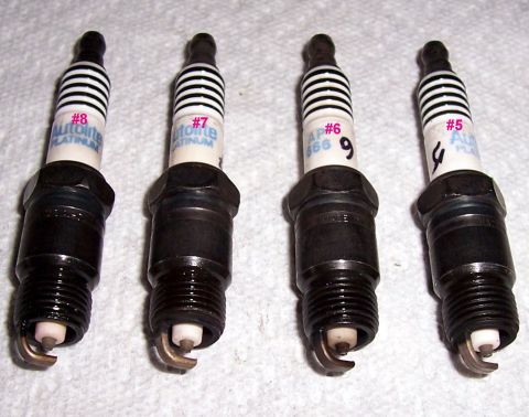 1978 Ford Mustang II - A set of four Autolite Platinum spark plugs are laid out on a white surface.