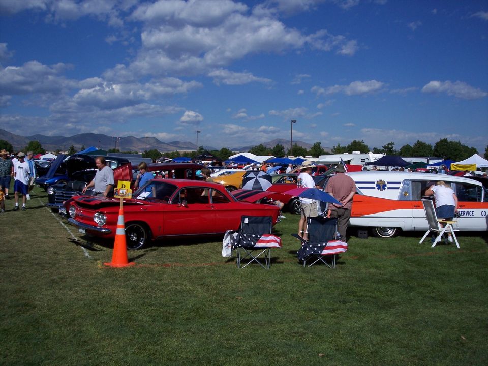 Red coupe with hood open, parked on grass next to an ambulance with orange and white paint
