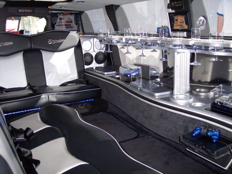1972 Ford Ranchero - The interior of a limousine features plush seating, a stocked bar, entertainment screens, and a gaming console.