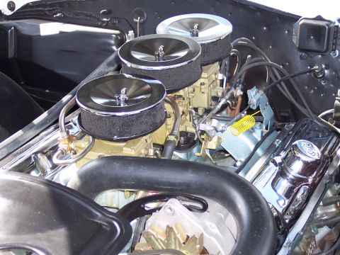 1972 Ford Ranchero - Close-up view of a V8 engine a triple carburetor setup and chrome valve covers.