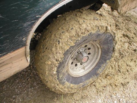 1990 Ford Bronco - The vehicle's tire and fender are heavily covered in mud, suggesting off-road use.