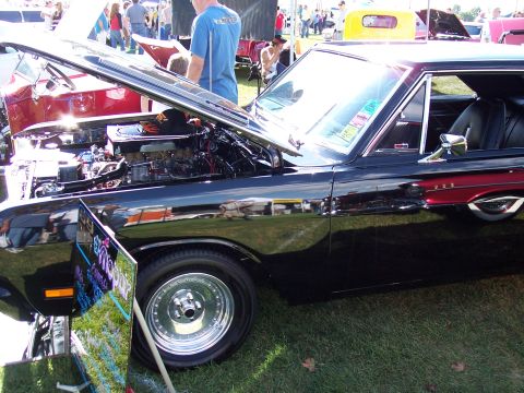 1972 Ford Ranchero - A black coupe with its hood open at an outdoor car show, displaying its engine and custom wheels.