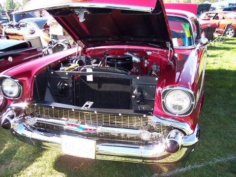 1972 Ford Ranchero - A gleaming red 1957 Chevrolet Bel Air is displayed with its hood open, revealing the engine bay.