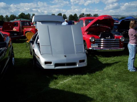 1972 Ford Ranchero - A silver sports car and a red pickup truck are displayed at an outdoor event.