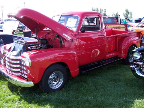 1972 Ford Ranchero - A classic red Chevrolet pickup truck is displayed with its hood open at an outdoor car show.