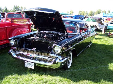 1972 Ford Ranchero - A black 1957 Chevrolet Bel Air is displayed with its hood open at an outdoor car show.