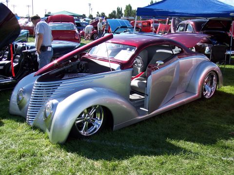 1972 Ford Ranchero - A highly customized coupe with a two-tone silver and maroon paint scheme is displayed with its hood and doors open at an outdoor car show.