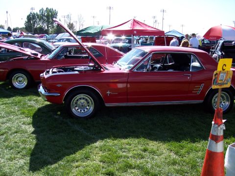 1972 Ford Ranchero - A red 1965 Ford Mustang coupe is displayed with its hood open at an outdoor car show, alongside other vehicles.