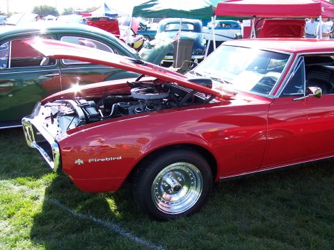 1972 Ford Ranchero - A red 1967 Firebird is displayed with its hood open, revealing the engine and polished chrome wheels.