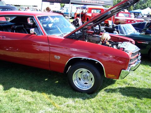 1972 Ford Ranchero - A red muscle car, possibly a 1970 Chevelle SS, is displayed with its hood open at an outdoor car show.