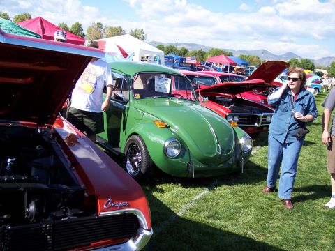1972 Ford Ranchero - A green Volkswagen Beetle is displayed at a car show, with other vehicles and tents visible in the background.