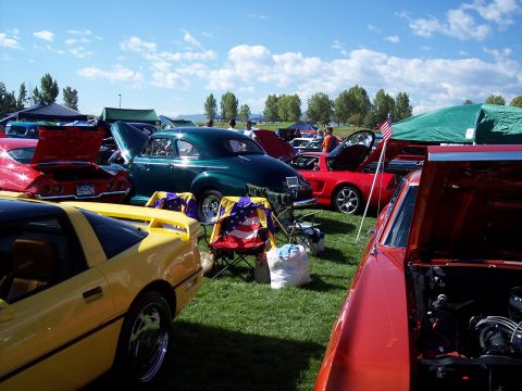 1972 Ford Ranchero - Several classic cars are displayed on a grassy field under a blue sky with scattered clouds.