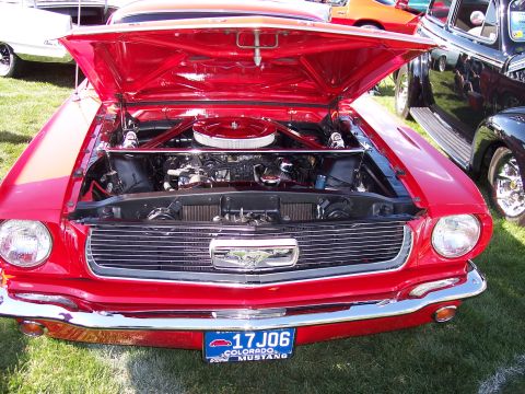 1972 Ford Ranchero - A bright red classic Ford Mustang is displayed with its hood up, revealing the engine bay and chrome details.