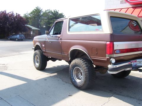 1990 Ford Bronco - This 1990 Ford Bronco is shown from the rear three-quarter angle, highlighting its brown paint and tan removable top.