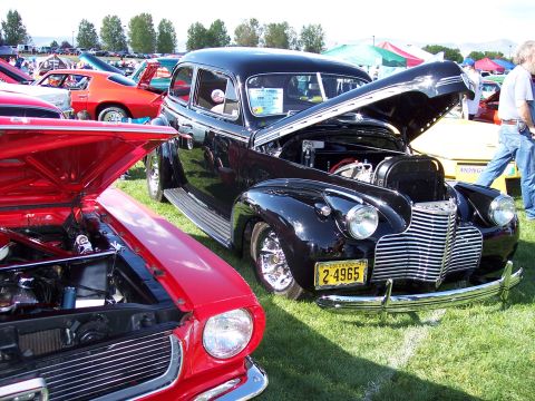 1972 Ford Ranchero - A black sedan from the 1940s is displayed with its hood open at an outdoor car show.