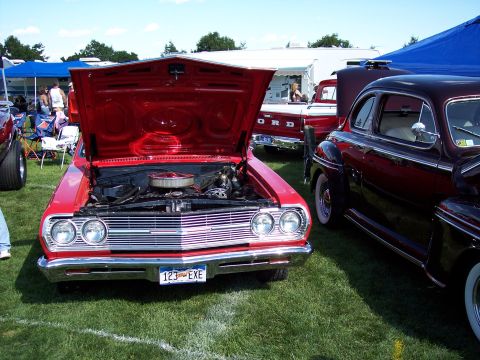 1972 Ford Ranchero - A red classic car is displayed with its hood open at an outdoor event, alongside other vintage vehicles.