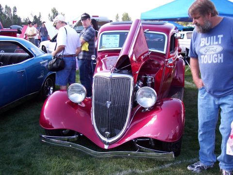 1972 Ford Ranchero - A classic red coupe, possibly a 1934 model, is displayed with its hood open at an outdoor car show.
