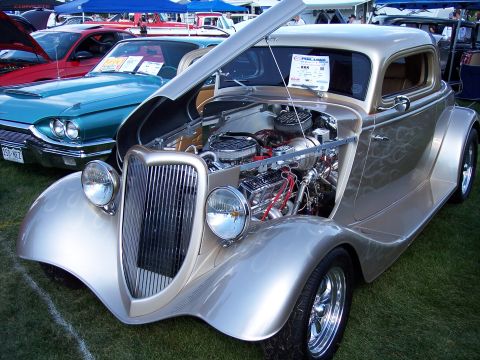 1972 Ford Ranchero - A custom hot rod coupe with its hood open, displaying a chrome engine, sits on grass at a car show.