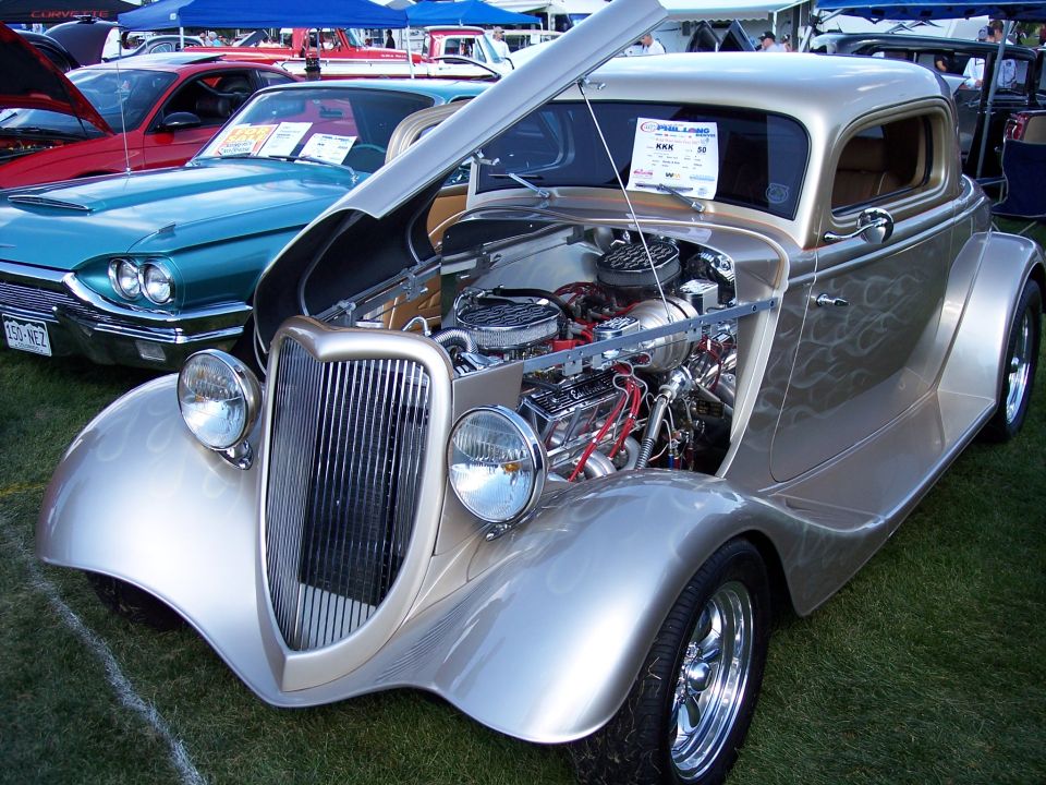 Gold hot rod coupe with flames, exposed engine, and chrome grille