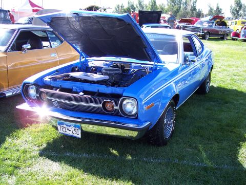 1972 Ford Ranchero - A blue 1970 AMC Gremlin X is displayed with its hood open at an outdoor car show.