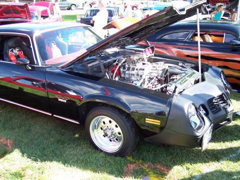 1972 Ford Ranchero - A black custom car with its hood open reveals a powerful chrome engine and racing seats, with '350' visible on the fender.