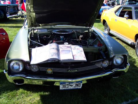 1972 Ford Ranchero - A 1969 AMC AMX is displayed with its hood open, revealing the engine and a book.