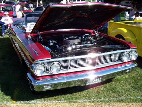 1972 Ford Ranchero - A classic red convertible is displayed with its hood open, revealing the engine bay. A yellow pickup truck is visible to the right.