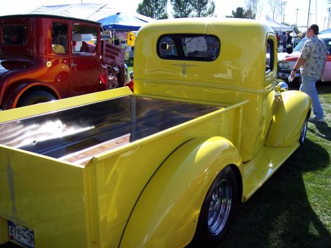 1972 Ford Ranchero - A bright yellow pickup truck is displayed at an outdoor event, with other vehicles and tents in the background.