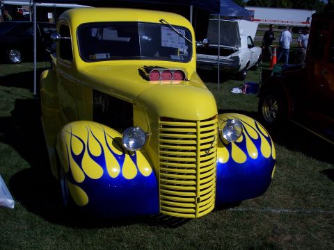 1972 Ford Ranchero - A bright yellow hot rod truck with custom flame paintwork is displayed outdoors.