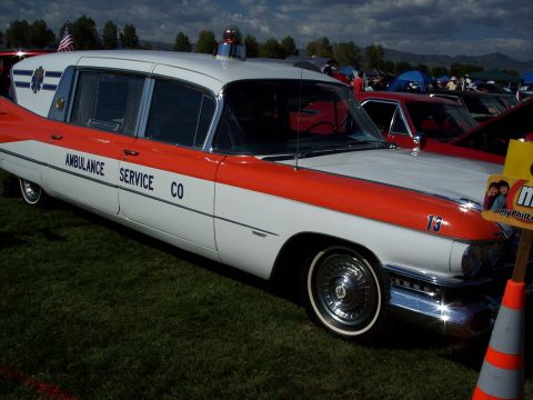 1972 Ford Ranchero - A vintage ambulance with an emergency light on top is displayed at an outdoor event with other vehicles in the background.