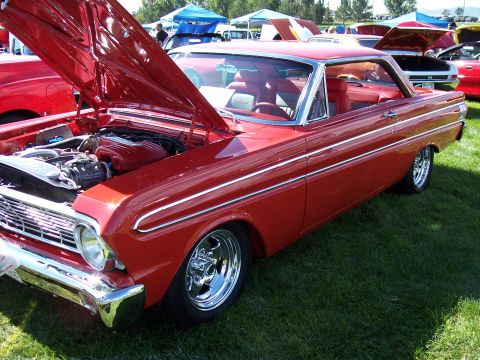 1972 Ford Ranchero - A red coupe with its hood open, displaying the engine and chrome accents on a grassy field.