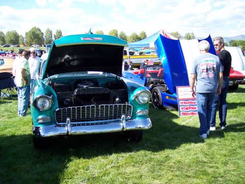 1972 Ford Ranchero - A turquoise 1955 Chevrolet Bel Air is displayed with its hood open at an outdoor car show.