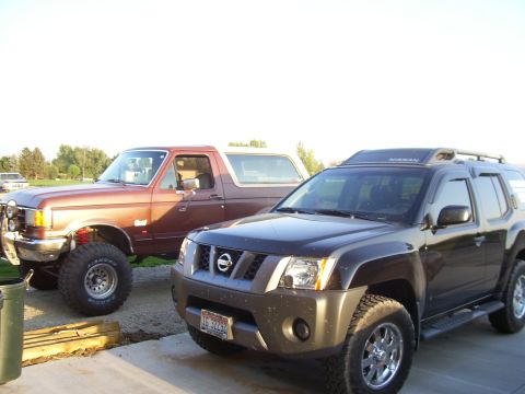 1990 Ford Bronco - Two SUVs, a 1990 Ford Bronco and a Nissan Xterra, are parked next to each other.